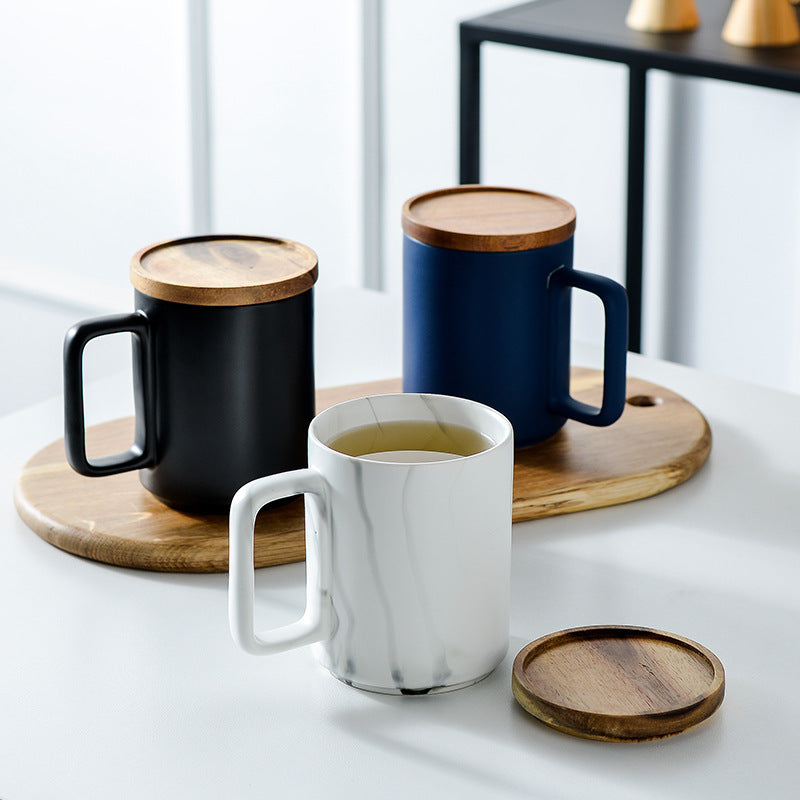 Three mugs with wooden lids on wooden coasters on a light surface.