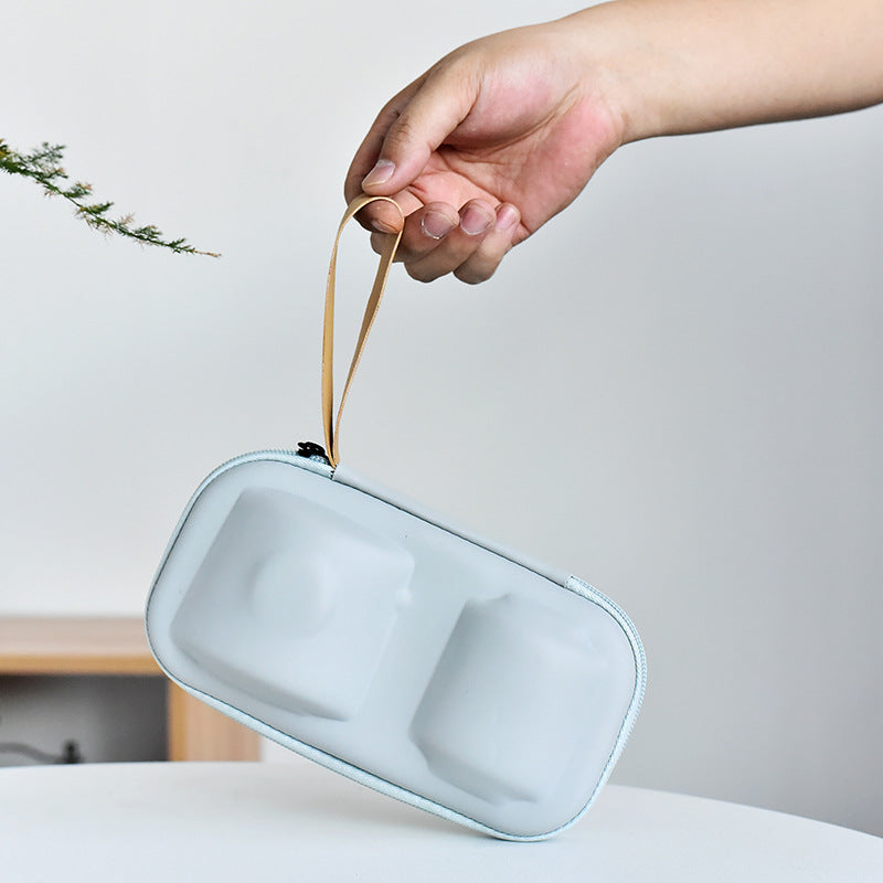 Hand holding a light blue pouch with a strap against a neutral background