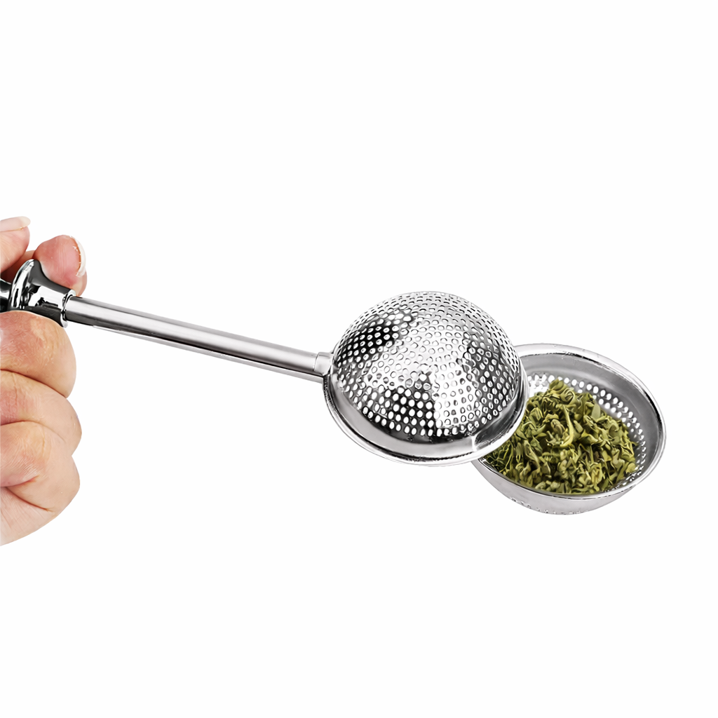 Metallic tea infuser with a small container of green tea leaves on a white background
