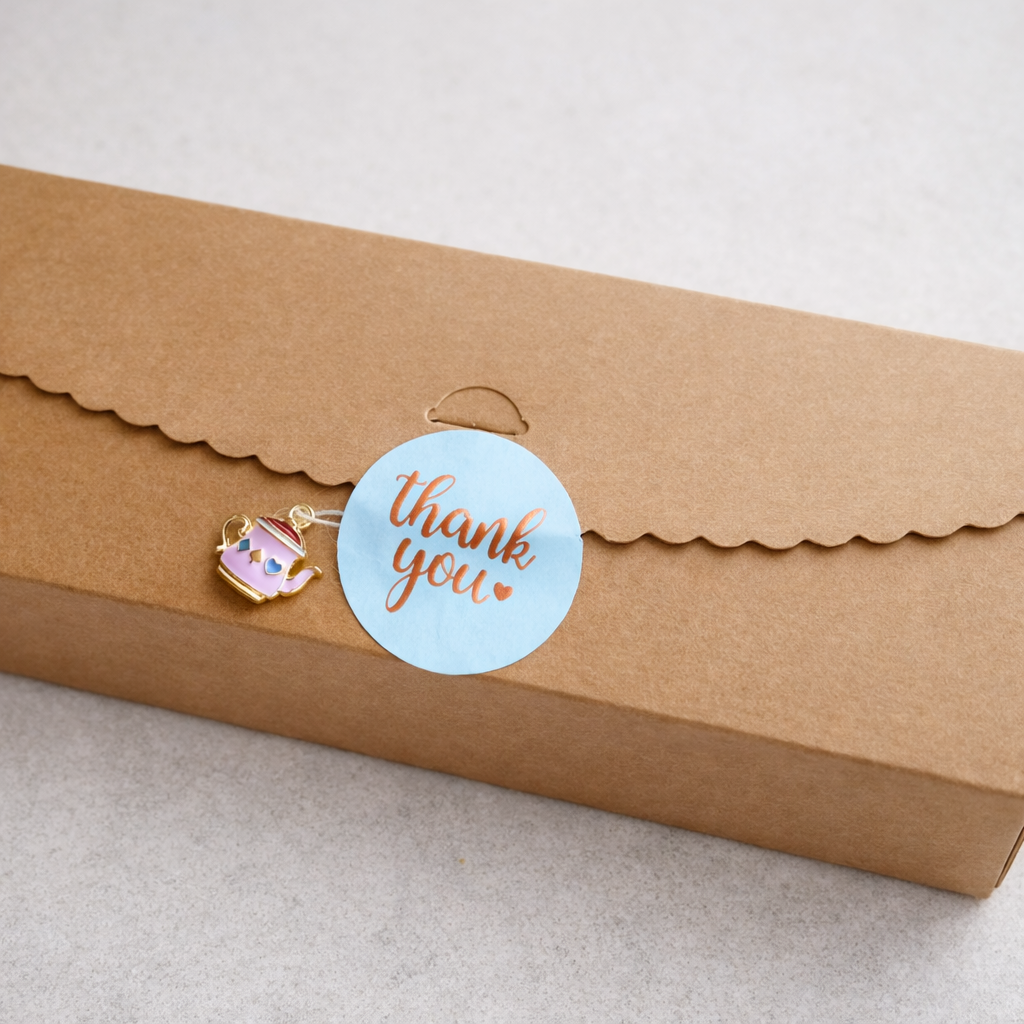 Kraft paper box with a 'thank you' sticker and decorative tag on a light background