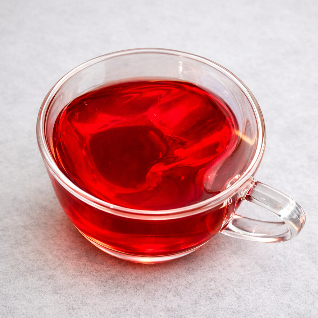 Clear glass mug filled with red liquid on a light gray background